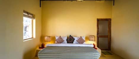 A bedroom with a bed, bedside lamps, a window, and a door.