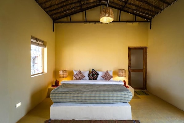 A bedroom with a bed, bedside lamps, a window, and a door.