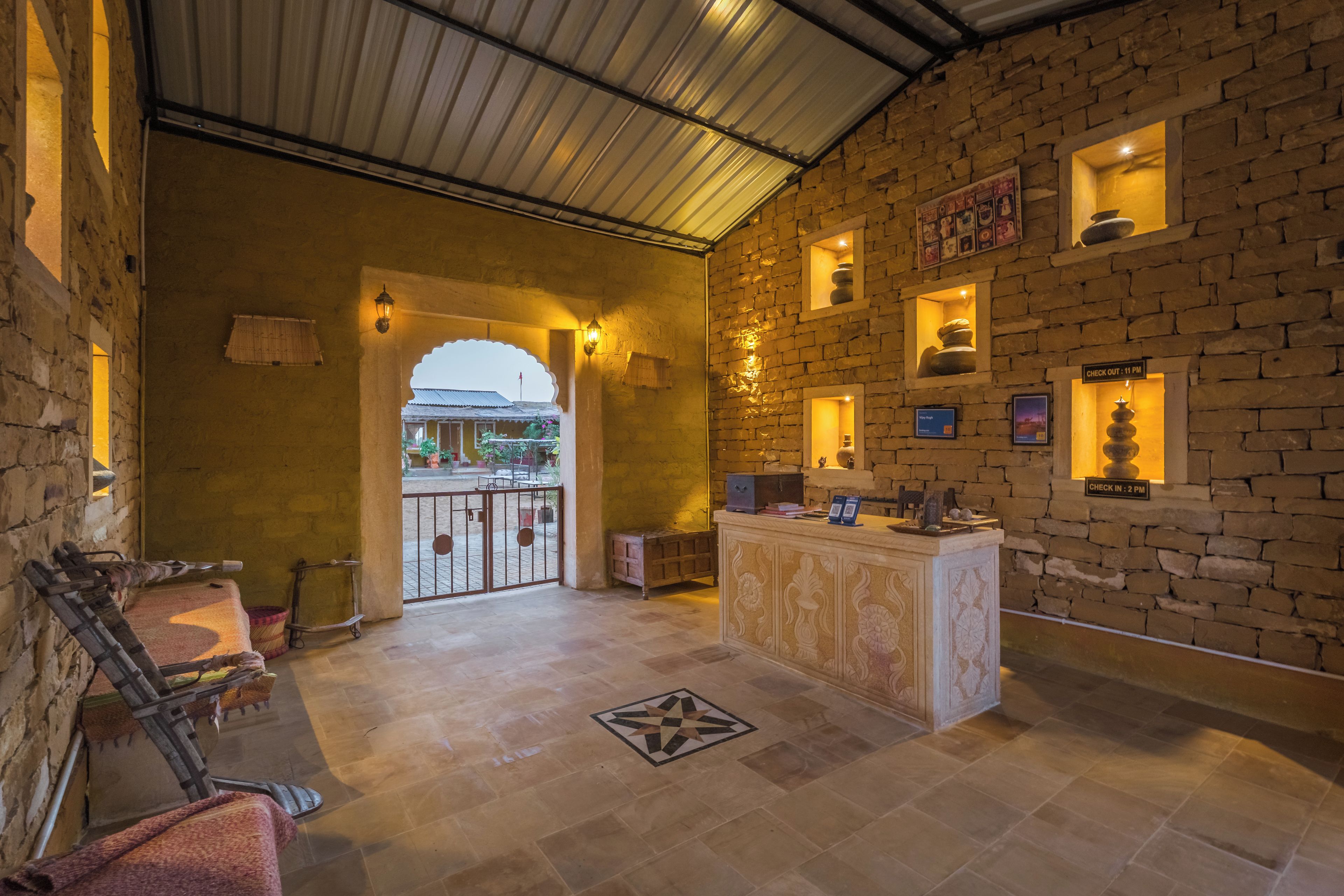 A lobby with a reception desk, stone walls, and a tiled floor.