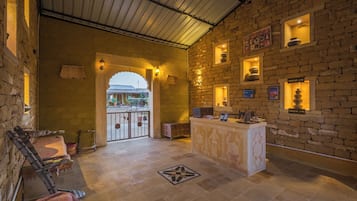 A lobby with a reception desk, stone walls, and a tiled floor.