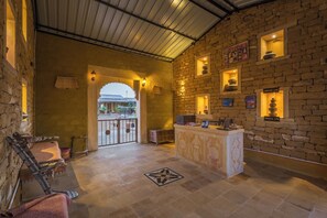 A lobby with a reception desk, stone walls, and a tiled floor. - Vijay Bagh Thar Village Resort (Jaisalmer)