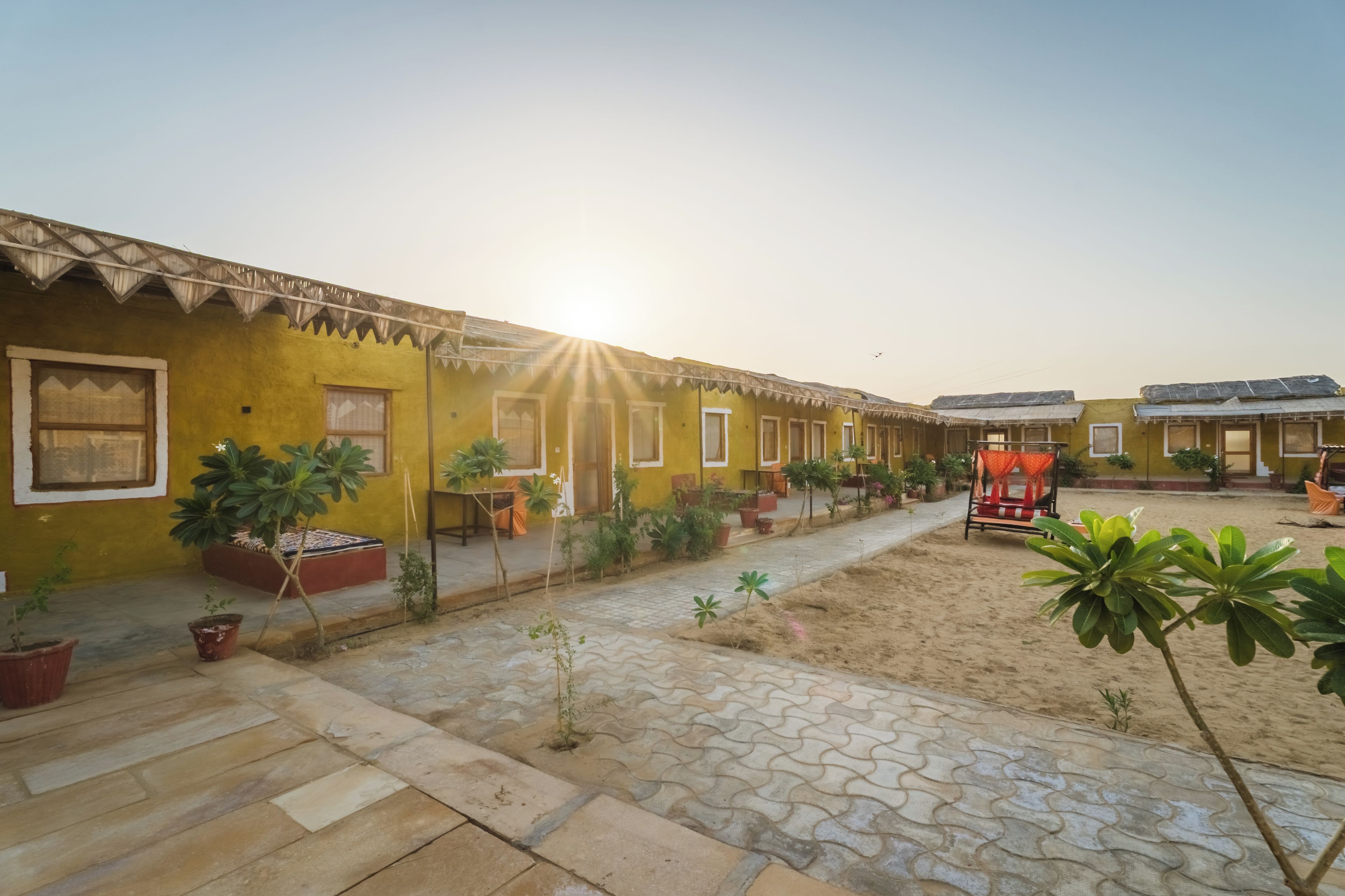 Un patio con edificios amarillos, plantas en macetas y un suelo de piedra estampada.