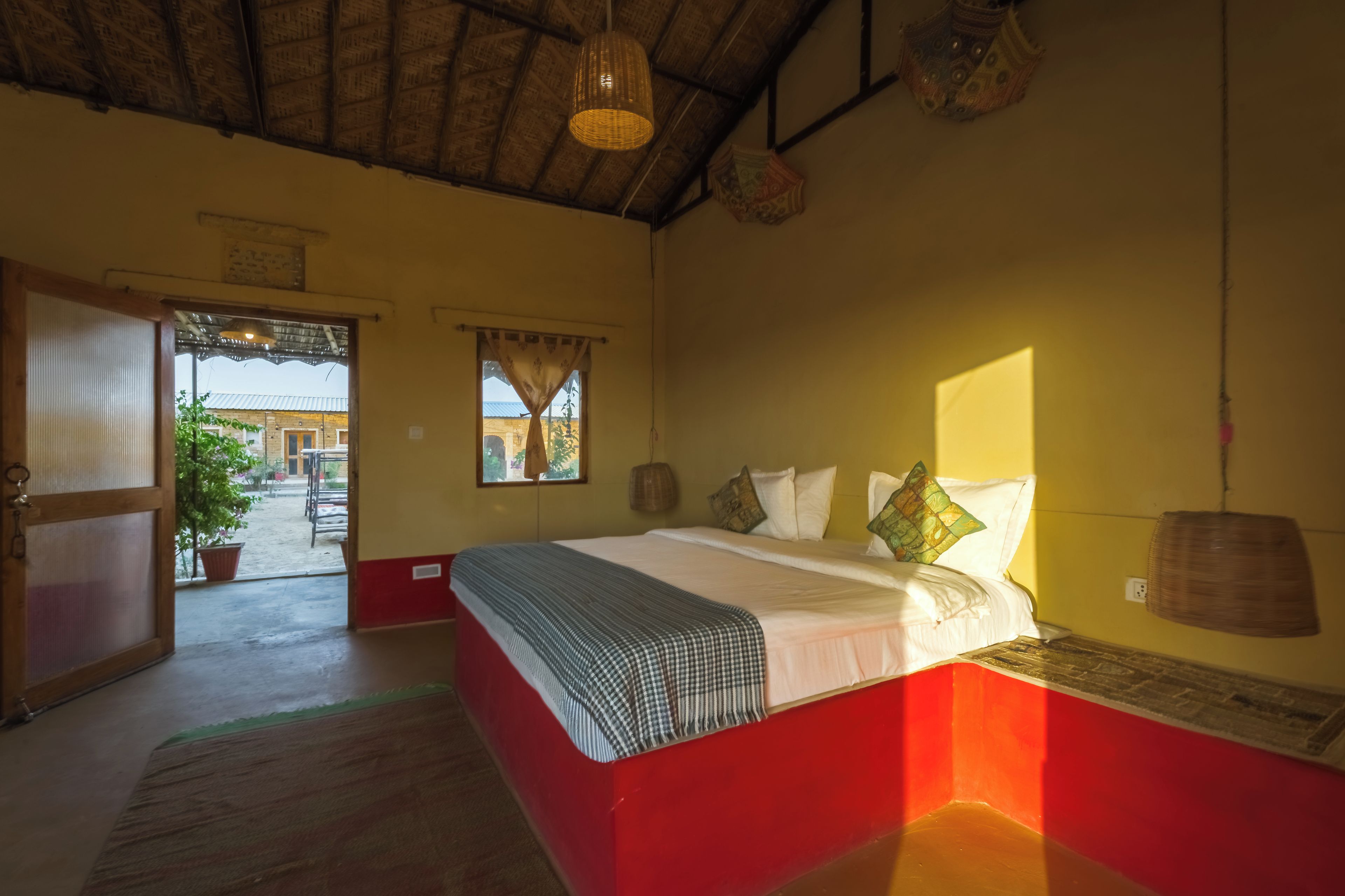 A bedroom with a bed, a window, and a door leading outside.