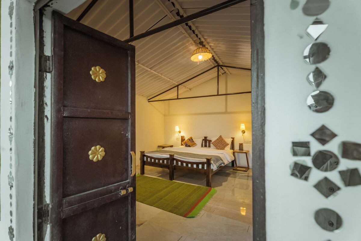A room with a bed, bedside lamps, a rug, and a door with decorative elements.