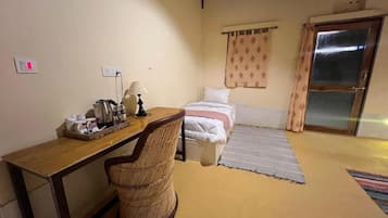 A room with a bed, a desk, a chair, a window with curtains, and a door.