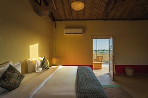 A room with a bed, a window, an air conditioning unit, and a view of the outside. - Vijay Bagh Thar Village Resort (Jaisalmer)