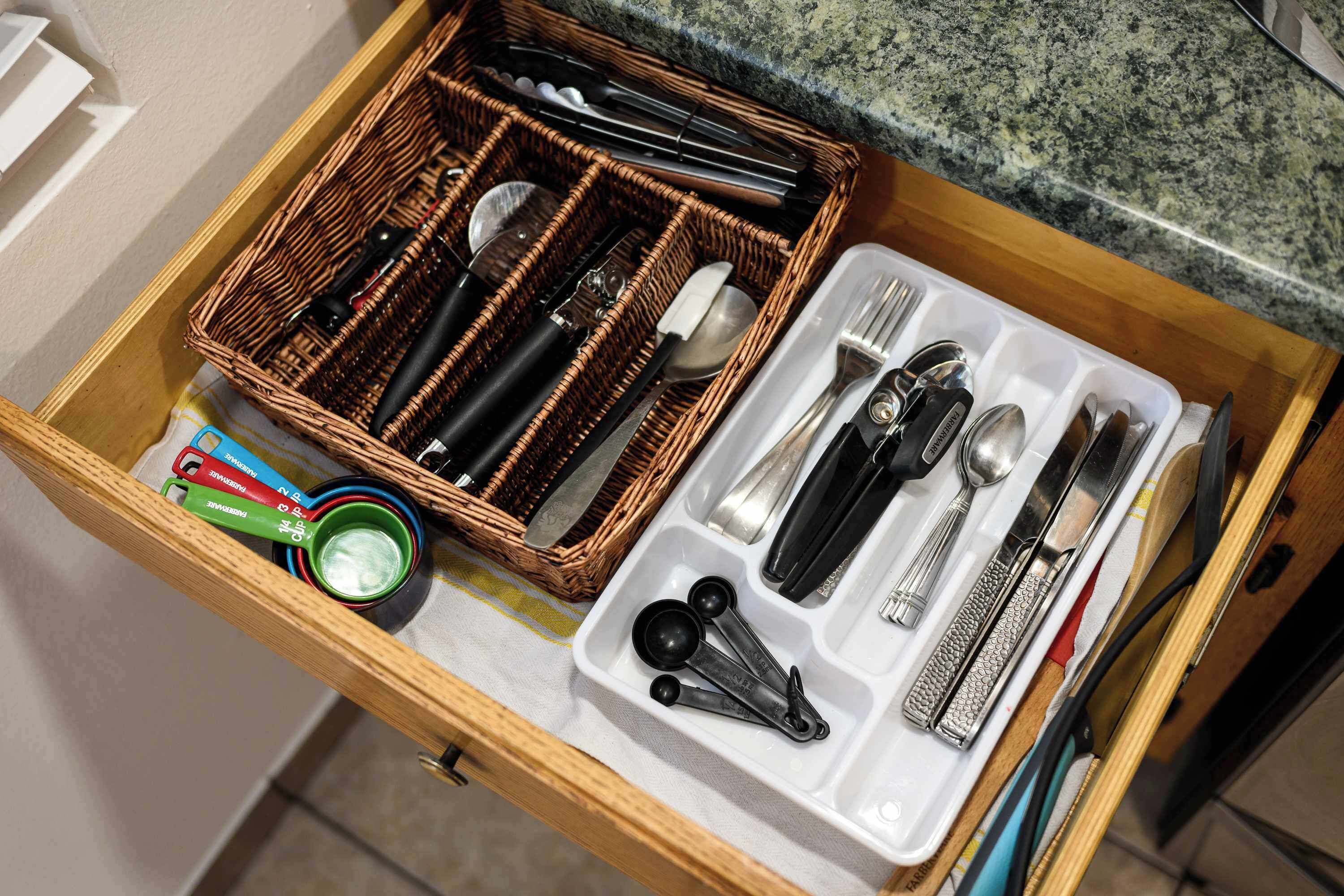 A kitchen drawer with utensils and measuring tools.