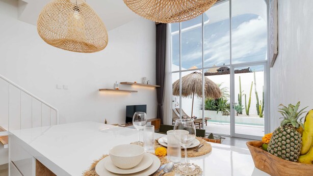 A modern kitchen with a large island, white cabinetry, and a view of the outdoors. - Villa Casa Zaya B (Canggu)