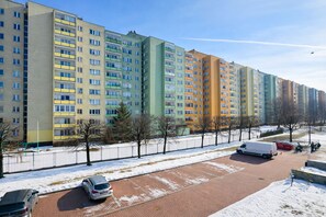 Una hilera de edificios residenciales de varios pisos con balcones, un camino pavimentado y suelo cubierto de nieve.