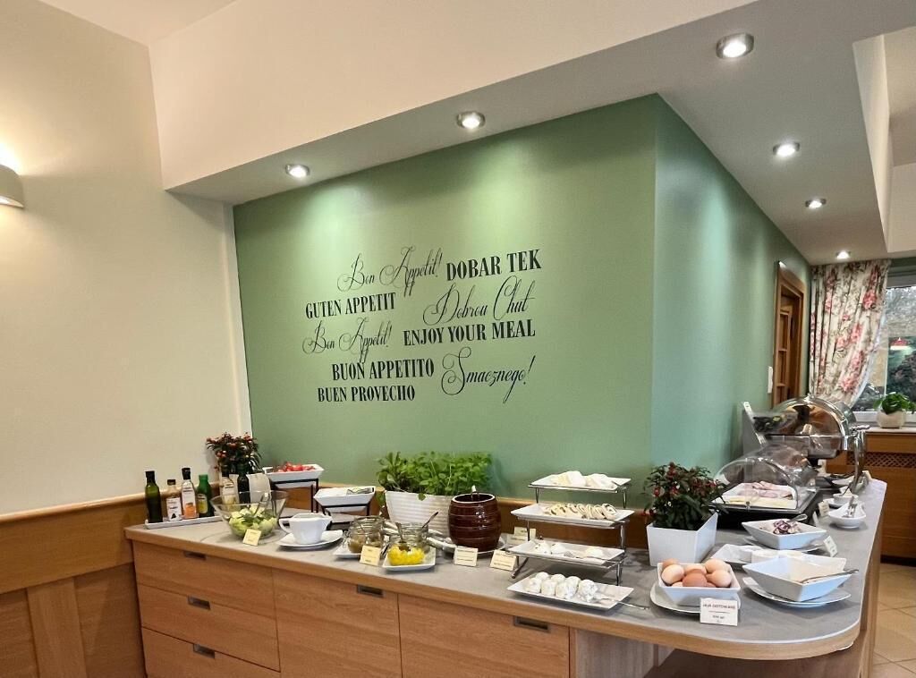 Ein reichhaltiges Buffet mit verschiedenen Speisen und einer Wand mit mehrsprachigen Hinweisen zum Thema Essen.
