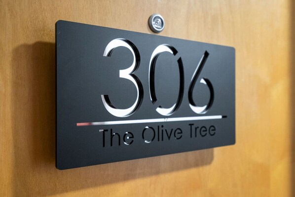 A black house number plaque with "306" and "The Olive Tree" on a wooden door. - Cosy Flat with River-view balcony, free secure parking, and city centre location (Leicester)