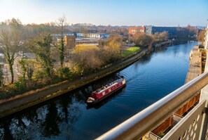 A river with a narrowboat, buildings, and a bridge in the background. - Cosy Flat with River-view balcony, free secure parking, and city centre location (Leicester)