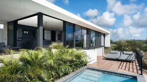 A modern house with a large glass balcony, a swimming pool, and lush greenery. - Villa Solara Cove Modern Design Luxury Nature (Sint Willibrordus)