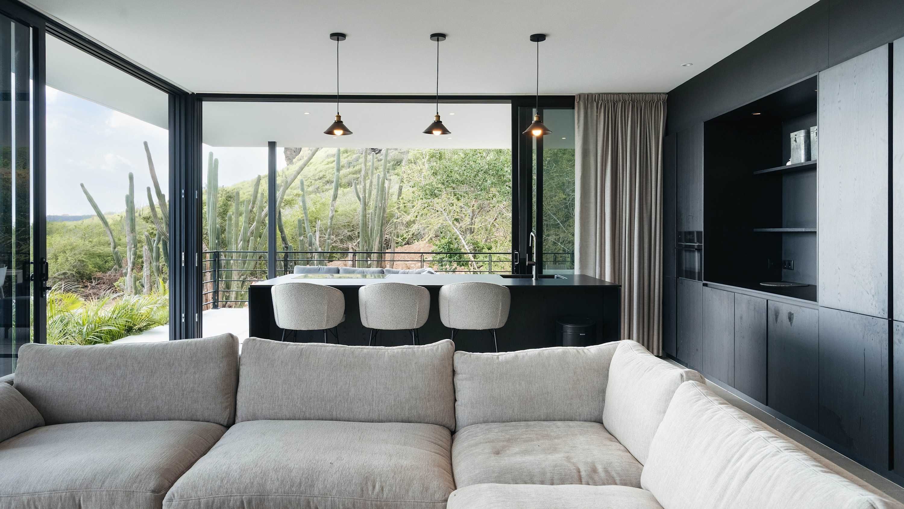 A modern living room with a large window, a sofa, and a bar area.