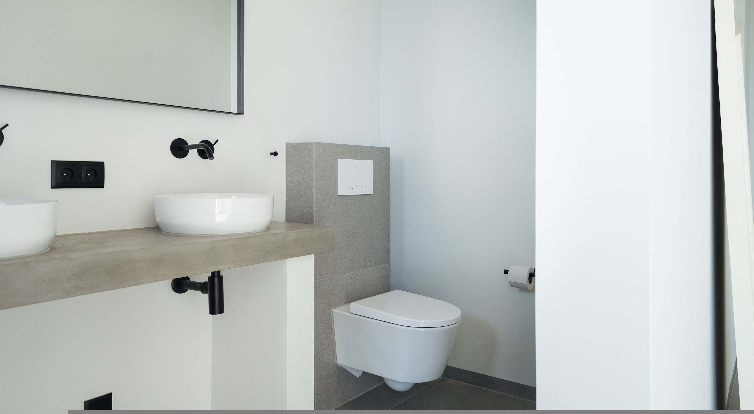 A modern bathroom with a white sink, a toilet, and a mirror.