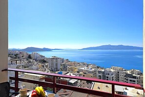 Un balcón con vistas a una ciudad costera, que incluye edificios y el mar.
