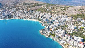 Vue aérienne d’une ville côtière caractérisée par une urbanisation dense, un port de plaisance et une mer d’un bleu limpide.