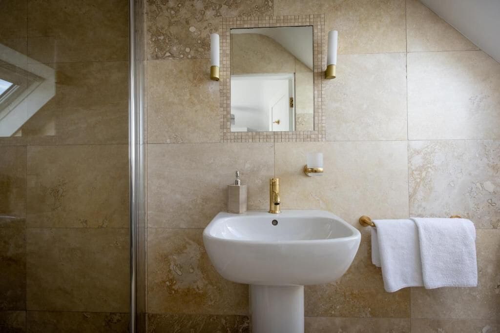 Un baño con lavamanos pedestal, un espejo y un perchero para toallas.