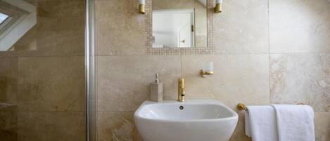 Un baño con lavamanos pedestal, un espejo y un perchero para toallas.