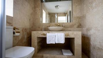 Un baño con un inodoro blanco, un lavamanos con espejo y un perchero para toallas.