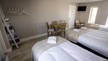 Una camera d'albergo con due letti, una scrivania con sedie, una televisione e una finestra.