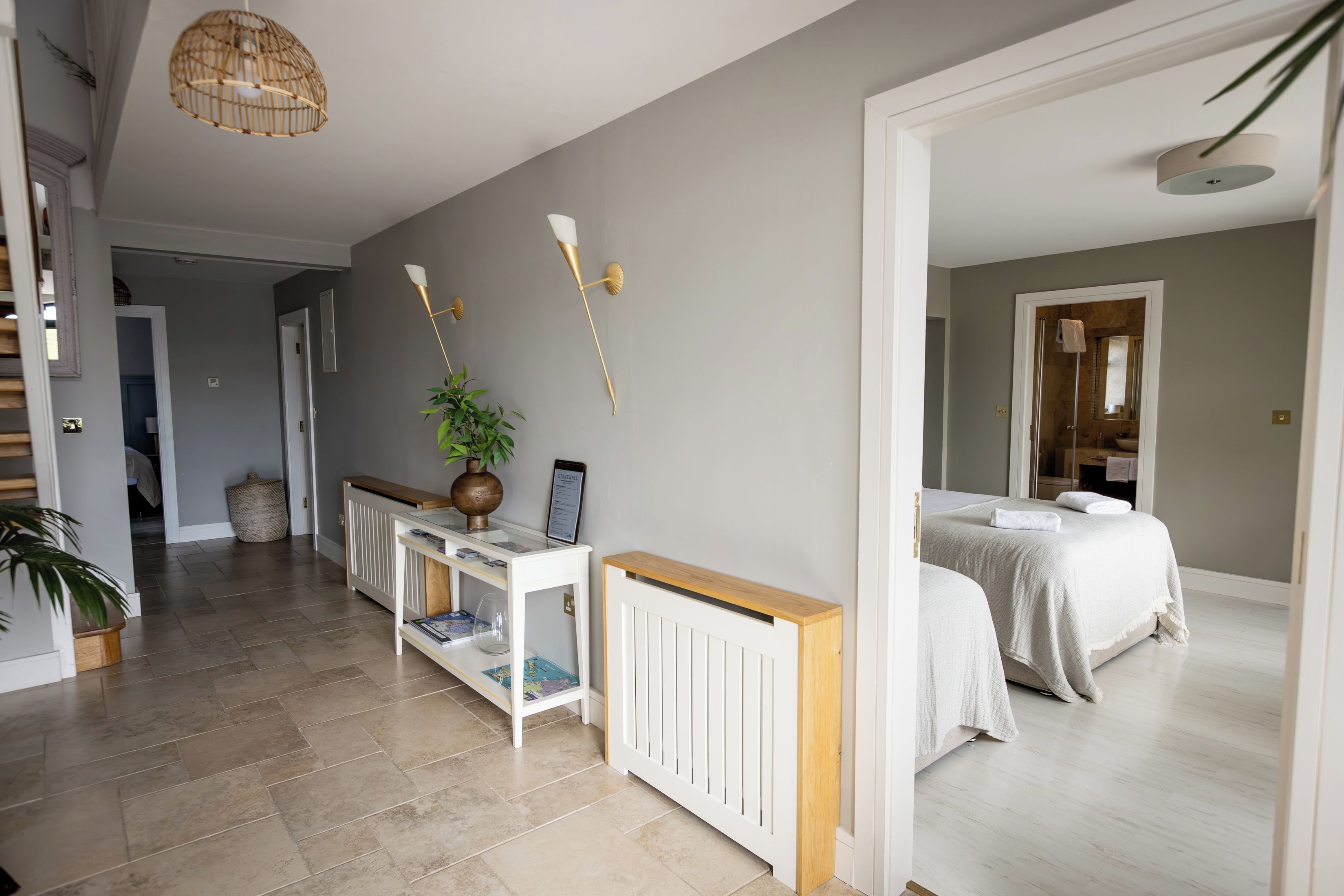 A hotel room with a bed, a bedside table, a radiator, a wall-mounted lamp, and a hanging light fixture.