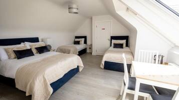 A bedroom with two beds, a desk, and a chair.