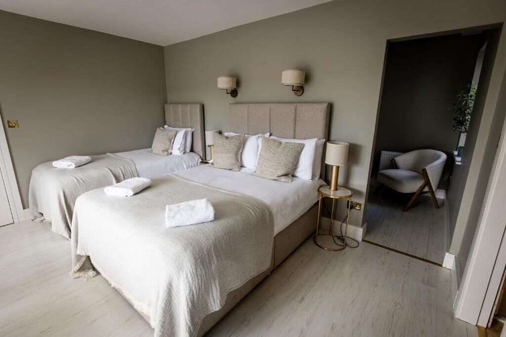 Habitación de hotel con dos camas, zona de estar y vistas al exterior.
