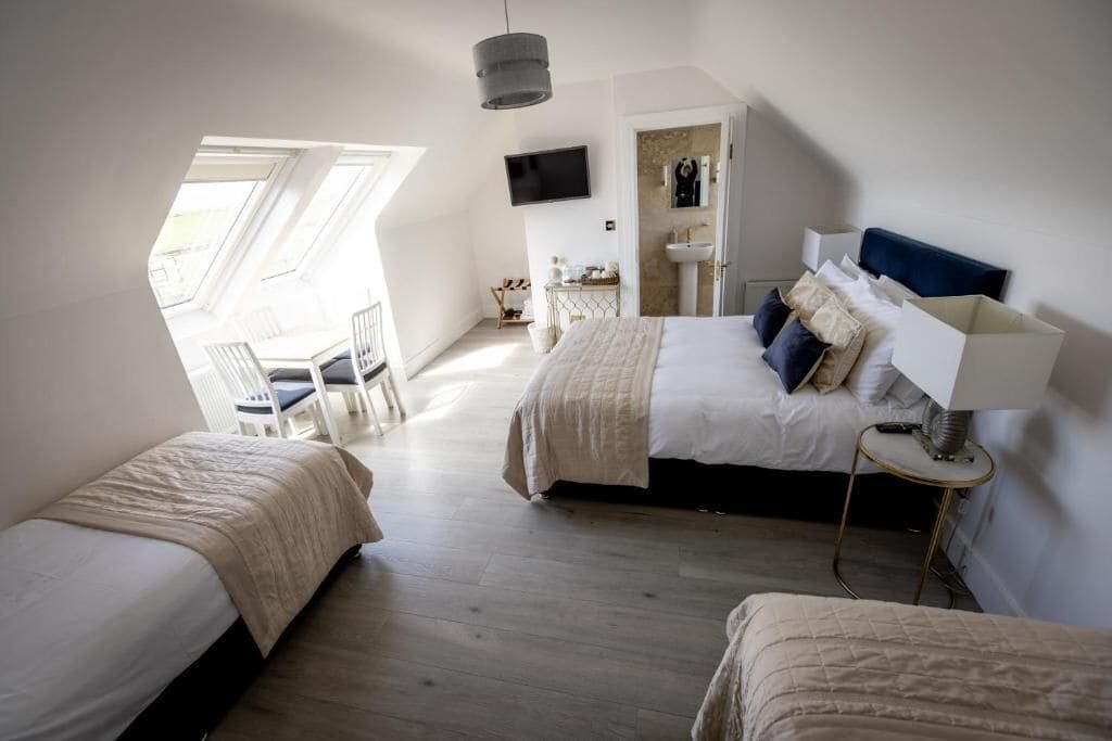 A bedroom with a large bed, a smaller bed, a TV, and a window with a view.
