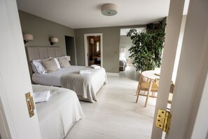 A modern hotel room with two beds, a dining area, and a large plant. - Coastal View House (Doolin)