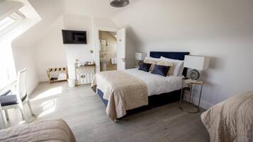 A bedroom with a bed, bedside table, lamp, and a TV mounted on the wall.