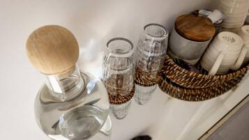 A kitchen counter with a wooden spoon, two glass containers, and a woven basket.