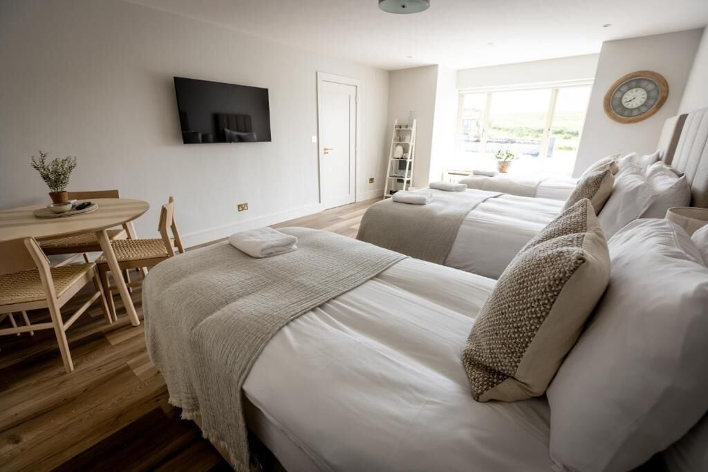 A hotel room with two beds, a desk with a chair, a TV, and a window with a view.