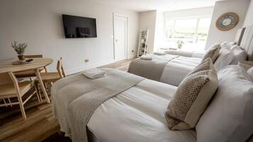 A hotel room with two beds, a desk with a chair, a TV, and a window with a view.