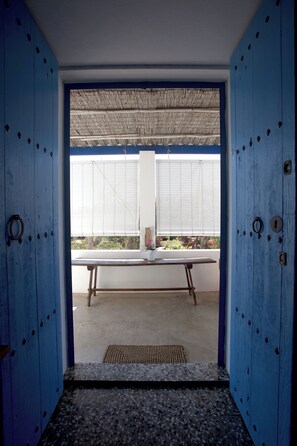 A room with a large window, a bench, and a door with blue panels.