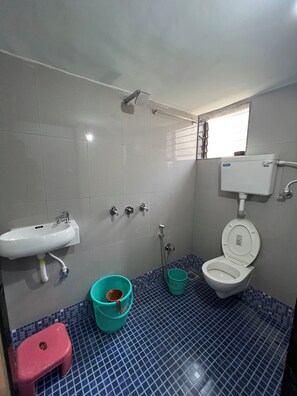 A bathroom with a sink, toilet, shower, and a small window. - Maooli Home Stay (Alibag)