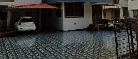 A multi-story residential building with a tiled driveway and a white car parked in the garage.