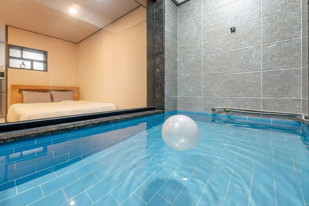 A hotel room with a large window, a bed, and a swimming pool with a water feature.