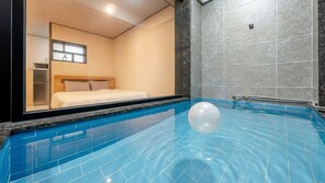 A hotel room with a large window, a bed, and a swimming pool with a water feature. - Gyeongju Bomun Arno Pool Villa (Gyeongju)