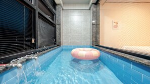 A swimming pool with a pink and white inflatable ring, tiled walls, and a closed shutter on the left. - Gyeongju Bomun Arno Pool Villa (Gyeongju)