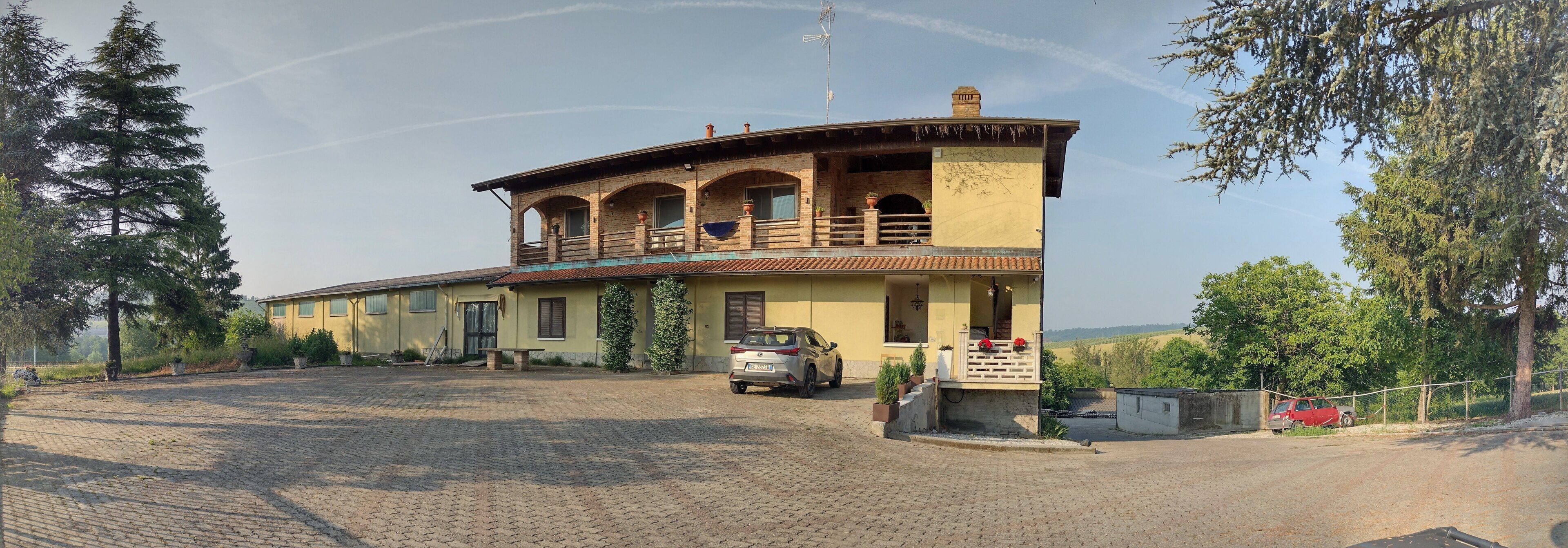 A two-story building with a balcony, a driveway, and parked cars.
