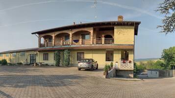 A two-story building with a balcony, a driveway, and parked cars.