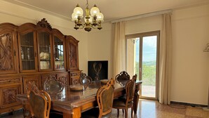 Une salle à manger avec une table et des chaises en bois, un grand buffet et un lustre.