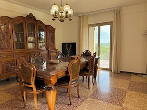 Un comedor con una mesa y sillas de madera, un aparador grande y una araña.