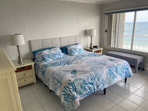 Ein Schlafzimmer mit einem Bett, zwei Nachttischen, einer Bank und Meerblick.