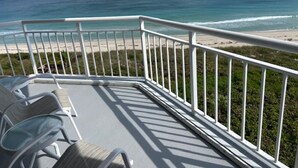 Ein Balkon mit weißen Geländern, der auf einen Strand blickt.