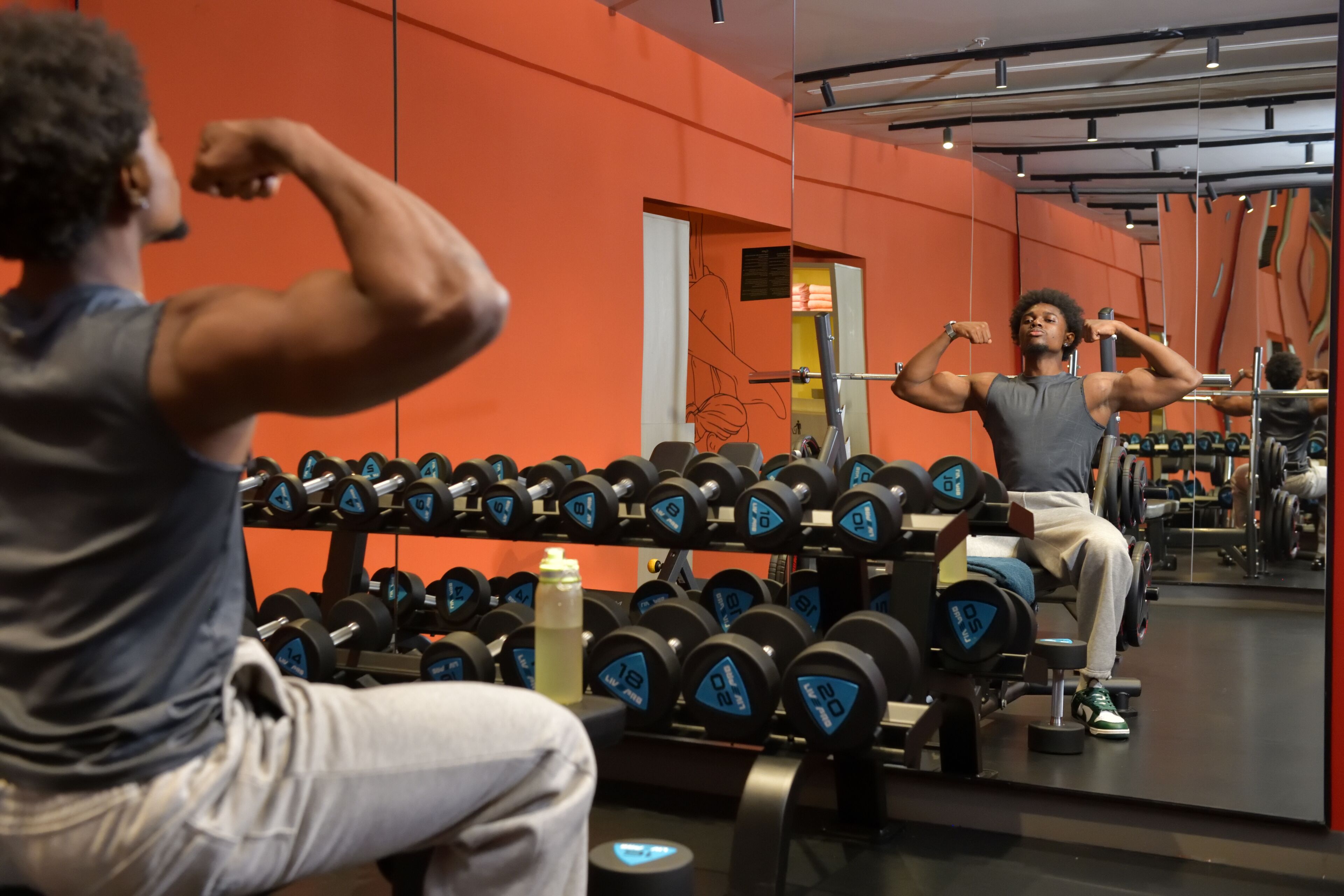 A gym with weightlifting equipment and a mirror.