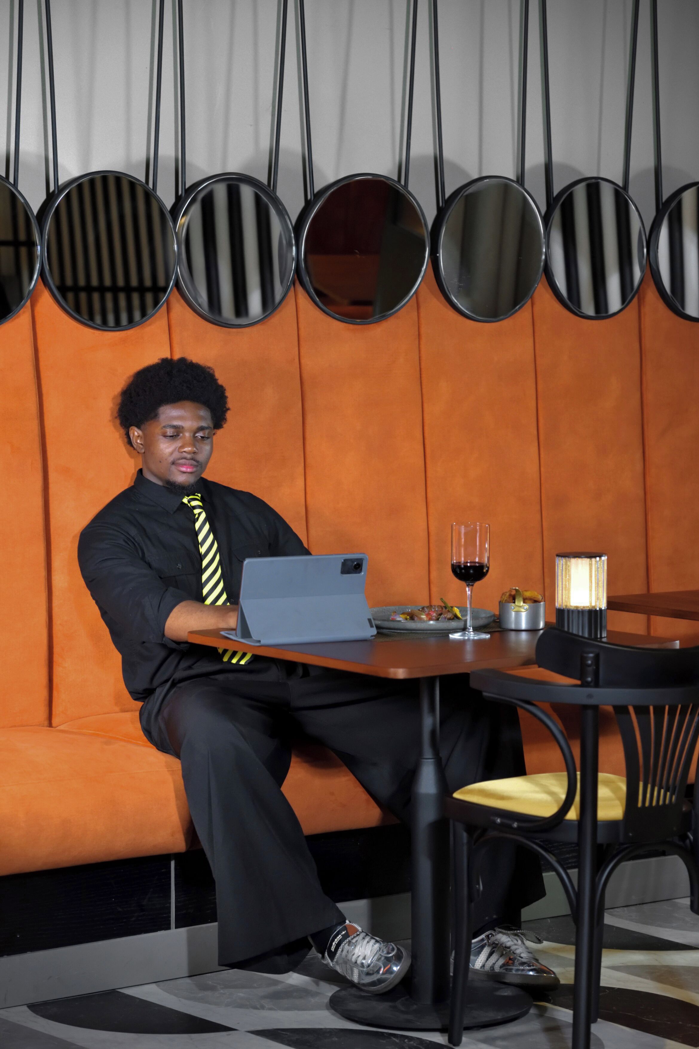 A person seated at a table with a laptop, a glass of red wine, and a candle.