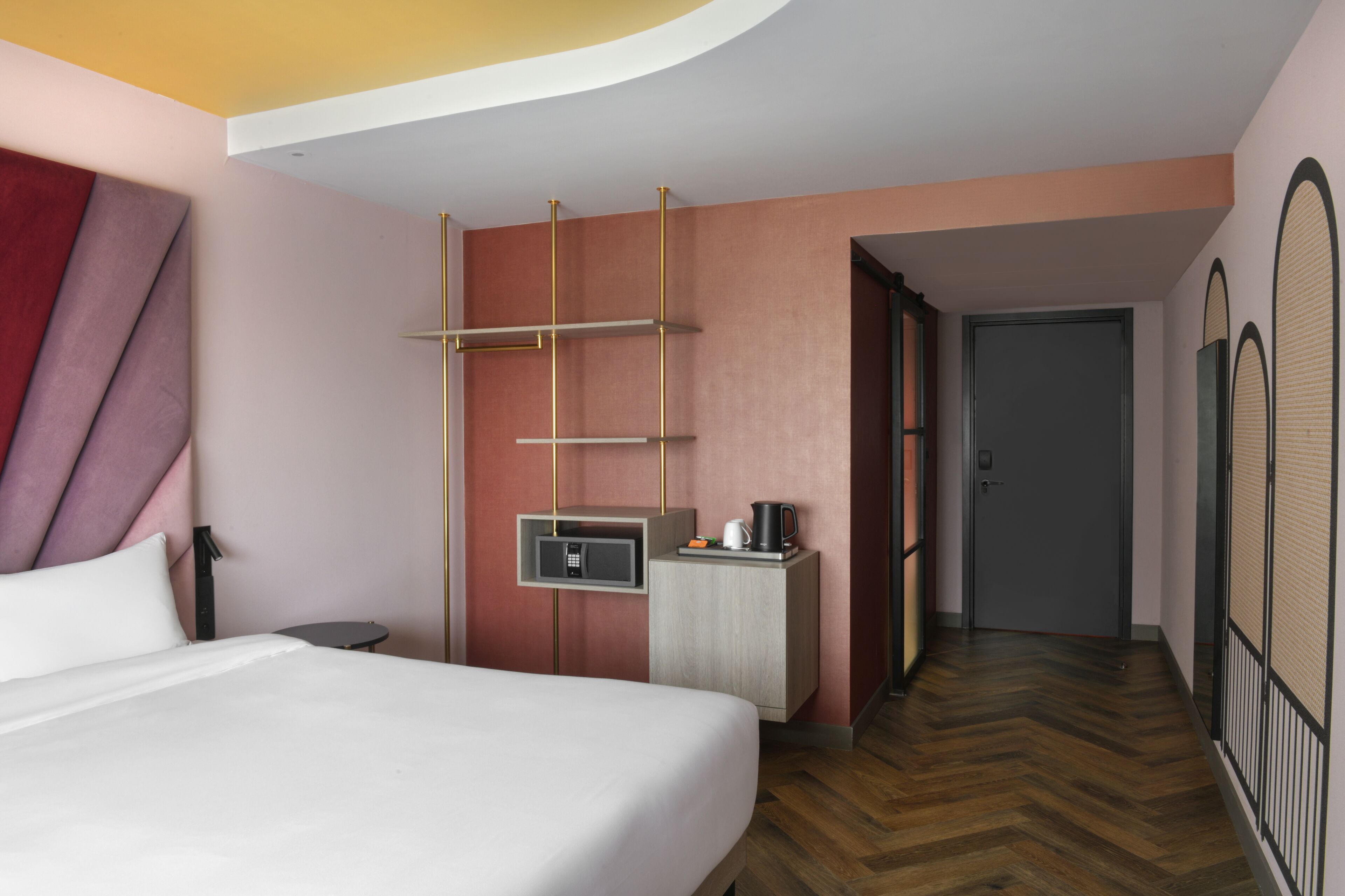 Habitación de hotel con cama, mesita de noche, un pequeño escritorio con microondas, cafetera y armario.