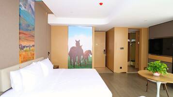 Habitación de hotel con una cama grande, un cuadro de caballos, un televisor y una pequeña mesa con una planta.
